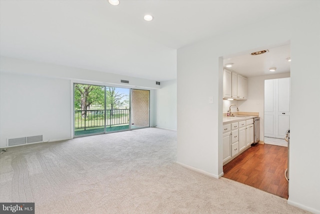 unfurnished living room featuring a sink, carpet, and visible vents