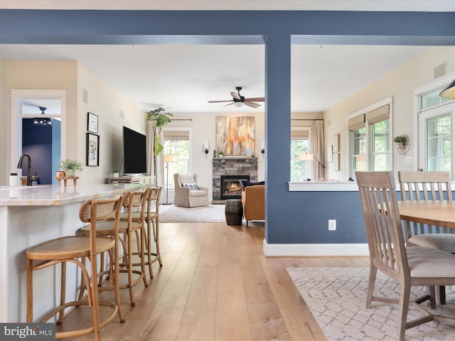 14484 Bluff Point Ct, Gainesville, VA 20155 - dining area featuring a ceiling fan, light wood-style floors, a fireplace, and baseboards