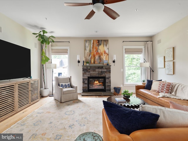 14484 Bluff Point Ct, Gainesville, VA 20155 - living room with healthy amount of natural light, a stone fireplace, wood finished floors, and ceiling fan