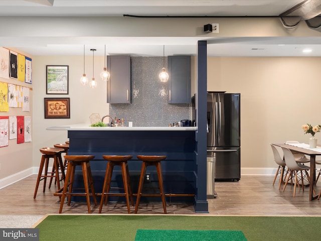 14484 Bluff Point Ct, Gainesville, VA 20155 - kitchen featuring stainless steel fridge, a kitchen bar, baseboards, decorative light fixtures, and light wood-type flooring