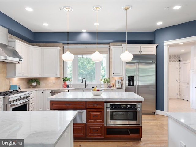 14484 Bluff Point Ct, Gainesville, VA 20155 - kitchen with high quality appliances, a sink, white cabinetry, light wood finished floors, and light stone countertops