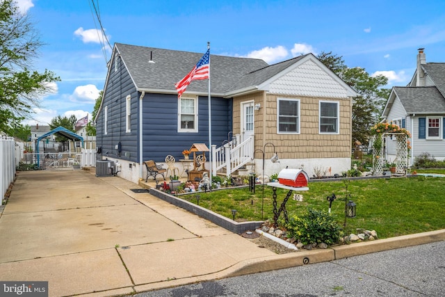 bungalow-style home with central air condition unit, roof with shingles, fence, a gazebo, and a front lawn