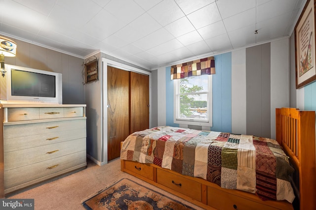carpeted bedroom with a closet and ornamental molding