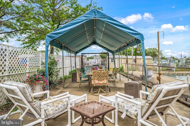 view of patio / terrace with a fenced backyard, outdoor dining space, an outdoor structure, and a storage shed