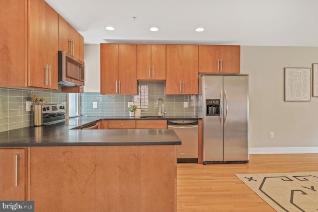 2515 17th St NW Unit 5, Washington, DC 20009 - kitchen with appliances with stainless steel finishes, a sink, light wood-type flooring, a peninsula, and dark countertops