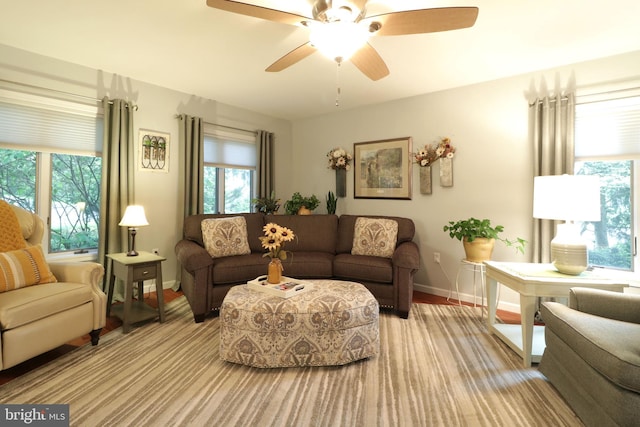 living area with light wood finished floors, plenty of natural light, baseboards, and a ceiling fan