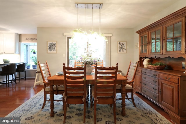 dining space featuring a chandelier, wood finished floors, and baseboards