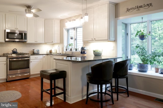 kitchen featuring visible vents, a sink, a kitchen breakfast bar, stainless steel appliances, and tasteful backsplash