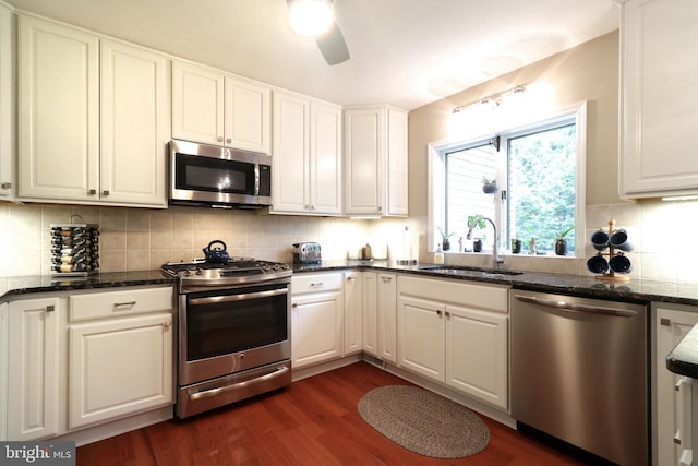 kitchen featuring dark wood finished floors, ceiling fan, a sink, decorative backsplash, and appliances with stainless steel finishes