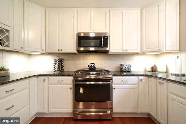 kitchen featuring white cabinets, appliances with stainless steel finishes, dark wood-type flooring, and backsplash