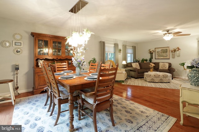 dining area featuring ceiling fan with notable chandelier, light wood-type flooring, and baseboards