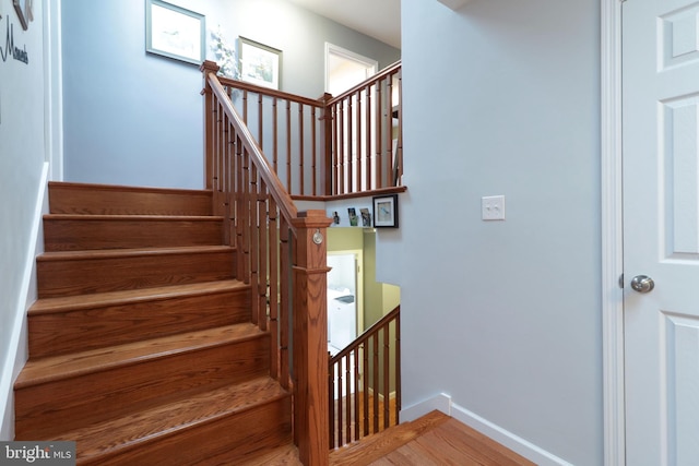 stairway with wood finished floors and baseboards