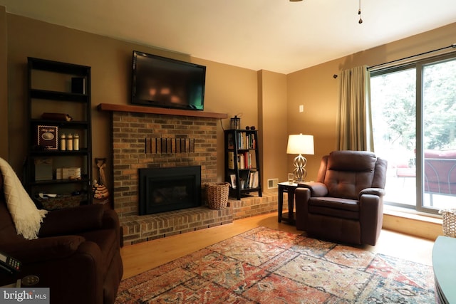 living area with visible vents, wood finished floors, a fireplace, and a healthy amount of sunlight