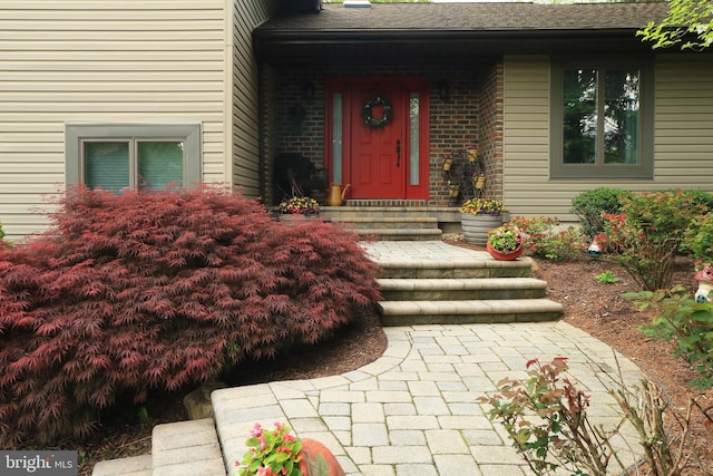 property entrance with brick siding and roof with shingles