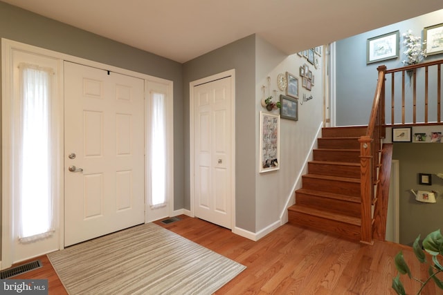 foyer entrance with stairway, light wood-style flooring, baseboards, and visible vents