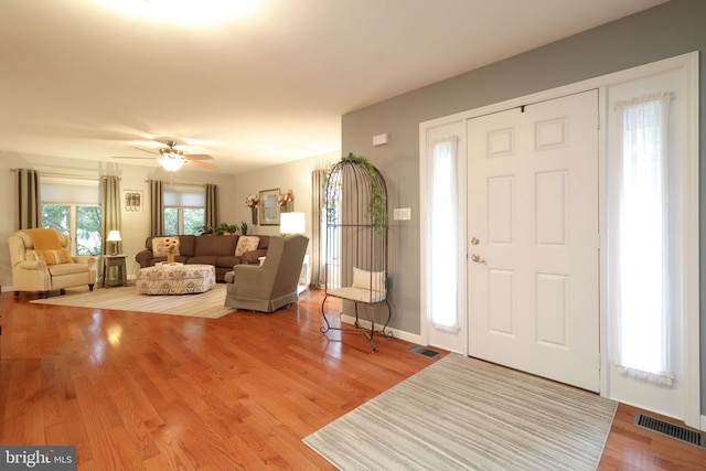 foyer entrance featuring ceiling fan, visible vents, and wood finished floors