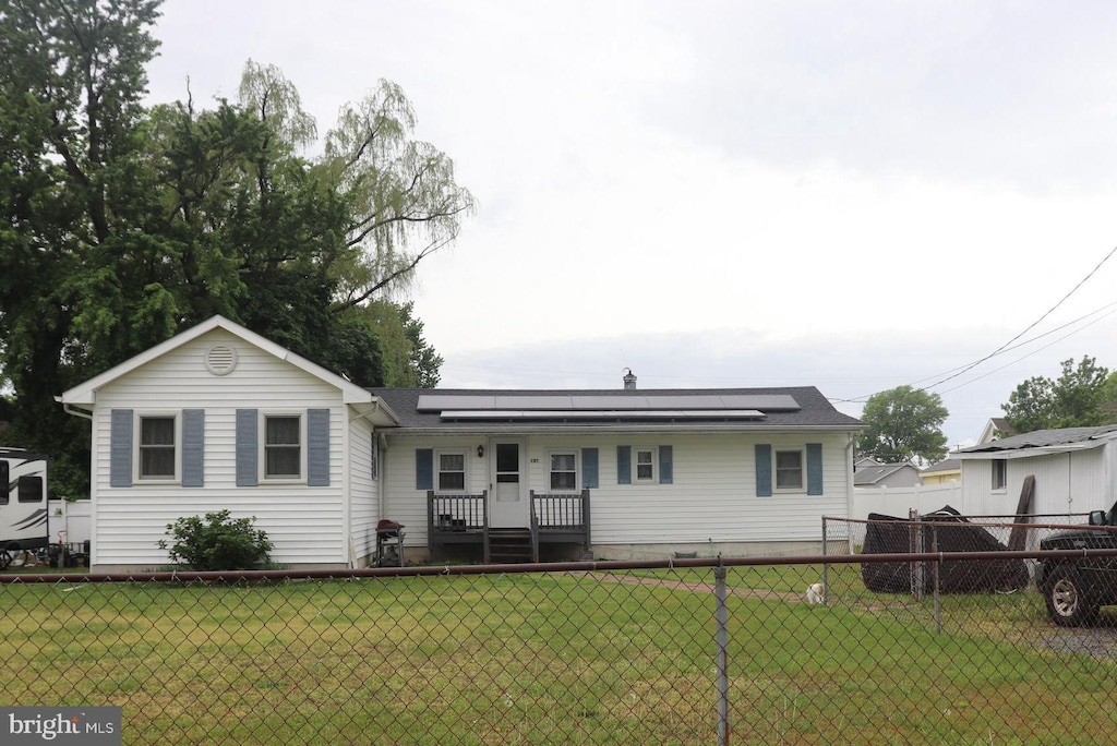 view of front of property featuring solar panels, a front yard, and fence private yard