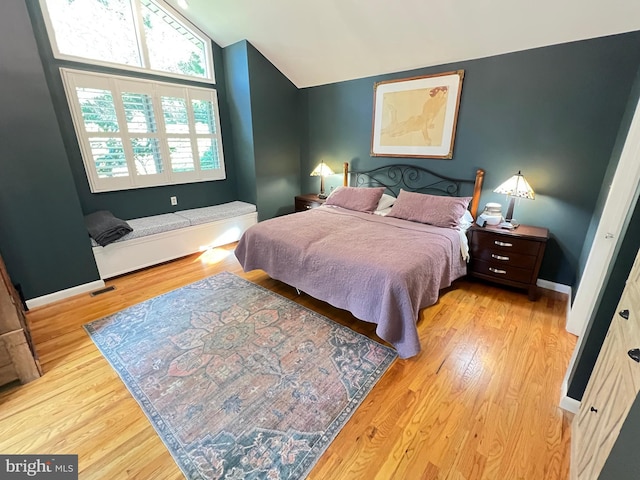 bedroom with vaulted ceiling, wood finished floors, and baseboards