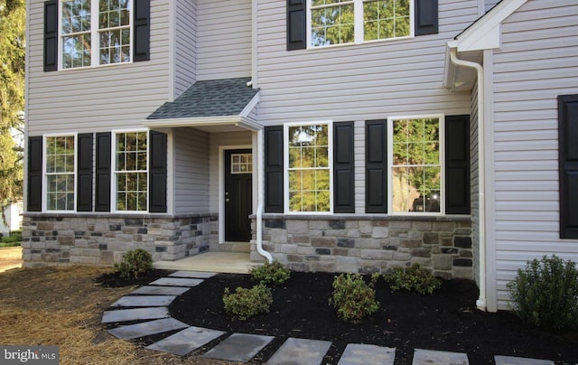 property entrance with stone siding and roof with shingles
