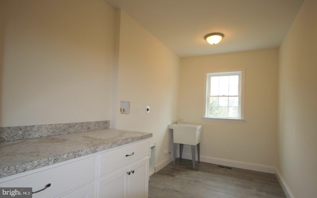 clothes washing area with washer hookup, light wood-type flooring, baseboards, electric dryer hookup, and cabinet space