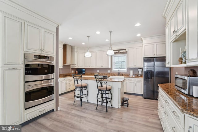 806 209th St, Pasadena, MD 21122 - kitchen with appliances with stainless steel finishes, a kitchen bar, a sink, wall chimney exhaust hood, and dark stone counters