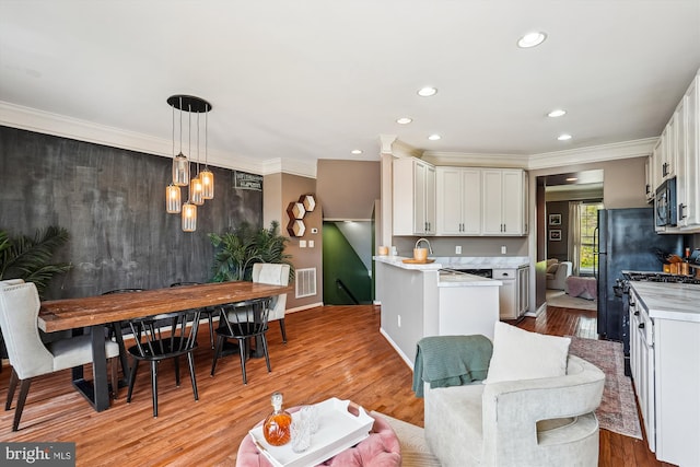 12205 Desoto Falls Ct, Bristow, VA 20136 - kitchen featuring black microwave, light countertops, light wood-style floors, recessed lighting, and ornamental molding