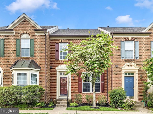townhome / multi-family property featuring brick siding and a shingled roof