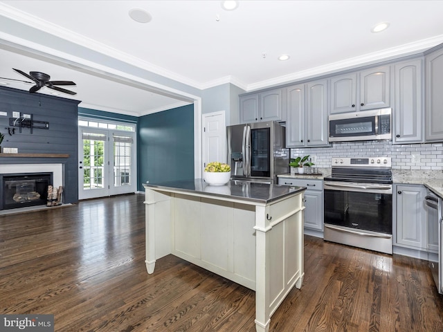 kitchen featuring appliances with stainless steel finishes, gray cabinets, tasteful backsplash, a center island, and dark wood-type flooring