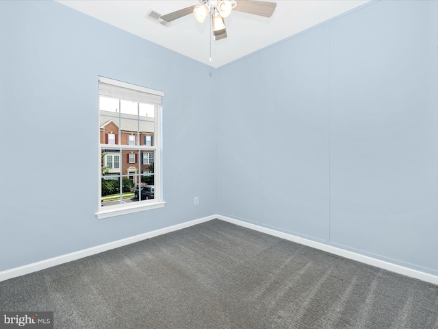 empty room featuring a ceiling fan, dark carpet, and baseboards