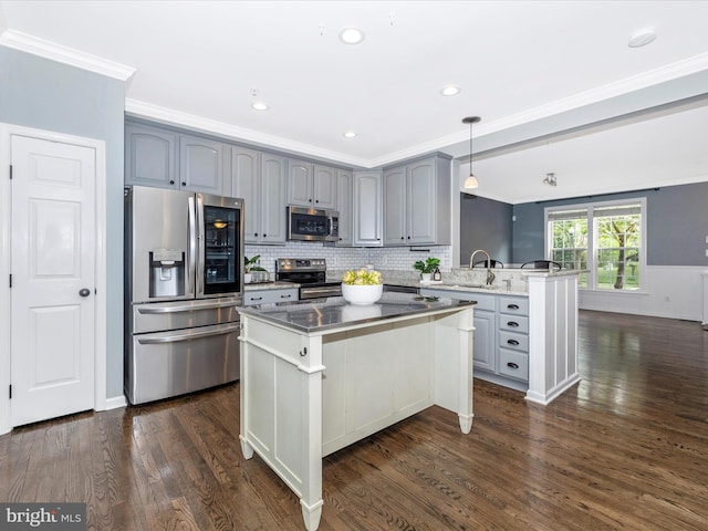 kitchen with appliances with stainless steel finishes, crown molding, gray cabinetry, a peninsula, and dark wood-type flooring