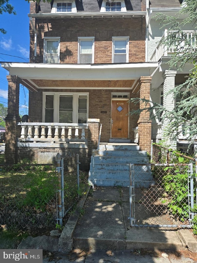 victorian home with mansard roof, brick siding, and a fenced front yard