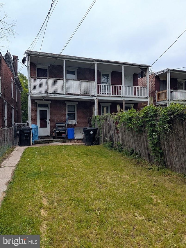 rear view of house with a lawn, brick siding, and fence