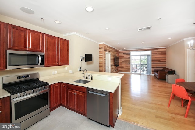 kitchen with stainless steel appliances, a sink, a peninsula, open floor plan, and dark brown cabinets
