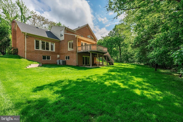 rear view of property with brick siding, a wooden deck, stairway, a chimney, and a lawn