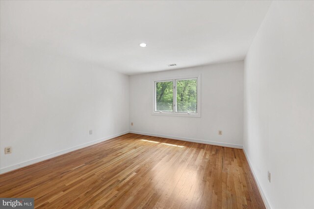 empty room with light wood-style flooring, baseboards, and recessed lighting