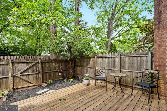 wooden terrace featuring a fenced backyard and a gate