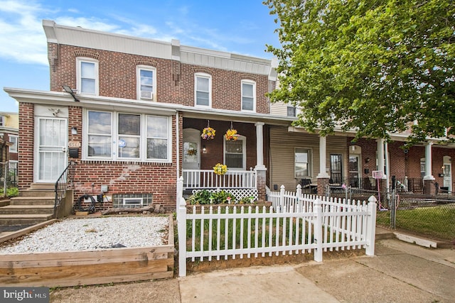 4558 Unruh Ave, Philadelphia, PA 19135 - view of property featuring a porch, a fenced front yard, brick siding, and entry steps