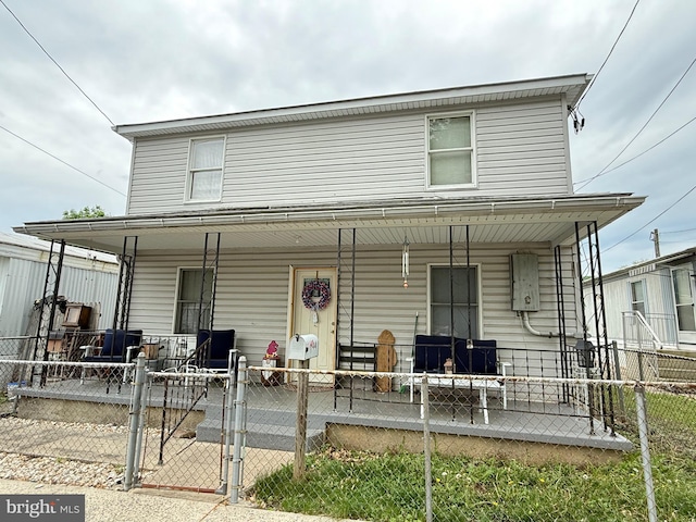 view of front of property featuring a fenced front yard, a porch, and a gate