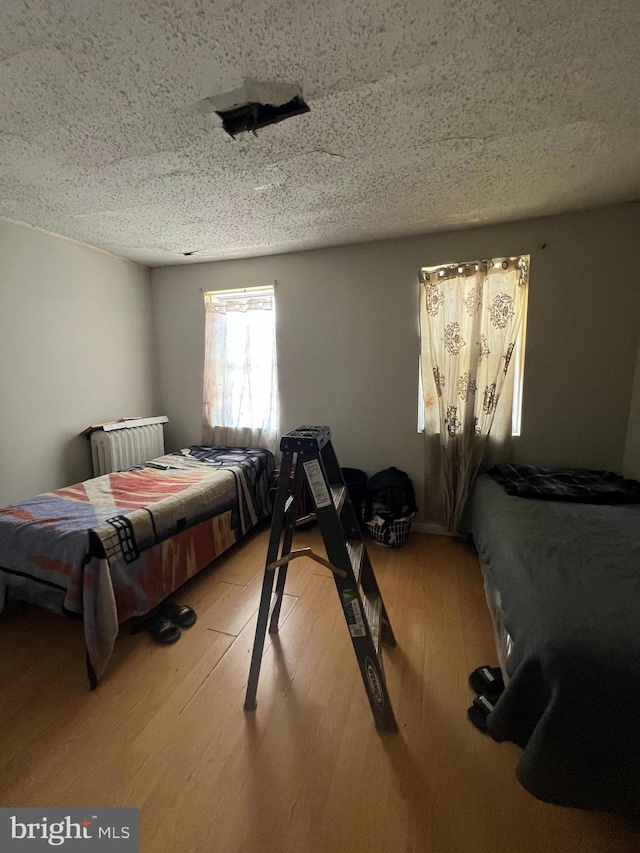 bedroom with light wood-style floors and a textured ceiling