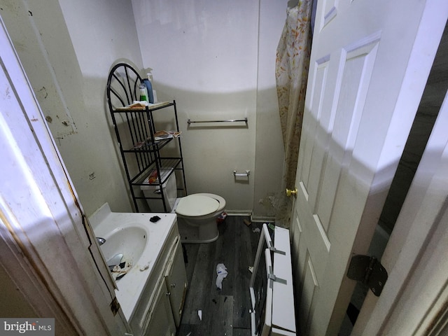 half bath featuring toilet, wood finished floors, and vanity