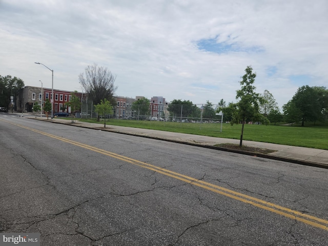 view of street featuring street lights, curbs, and sidewalks