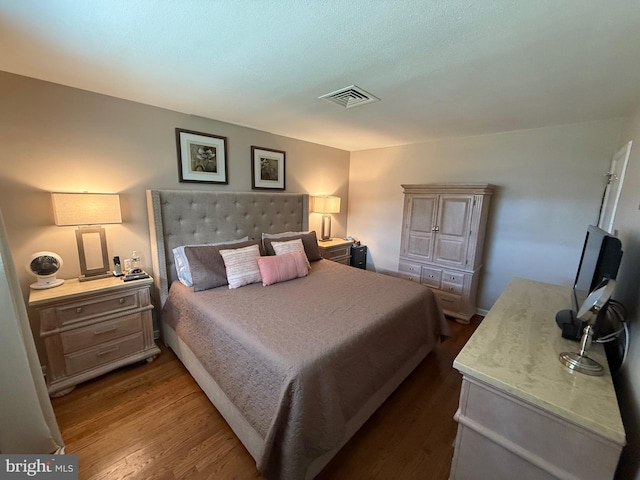 bedroom featuring visible vents and wood finished floors