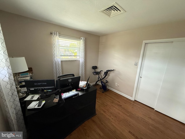 office area with dark wood-style flooring, baseboards, and visible vents