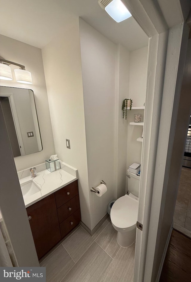 bathroom featuring vanity, toilet, and baseboards