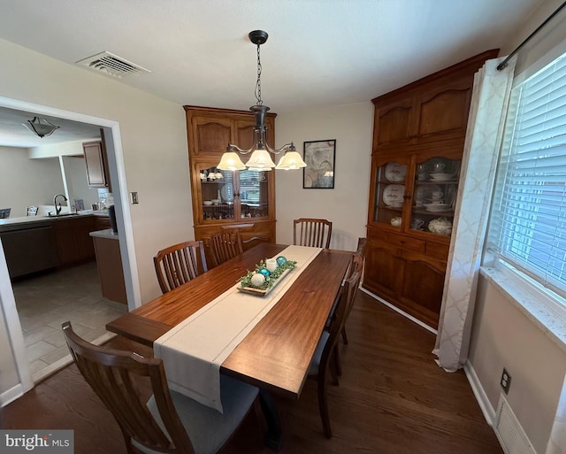 dining space featuring a chandelier, dark wood finished floors, visible vents, and a healthy amount of sunlight