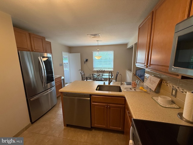 kitchen featuring a peninsula, a sink, stainless steel appliances, visible vents, and light countertops