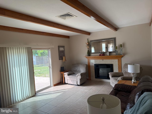 living area featuring a tile fireplace, light tile patterned floors, beam ceiling, visible vents, and baseboards