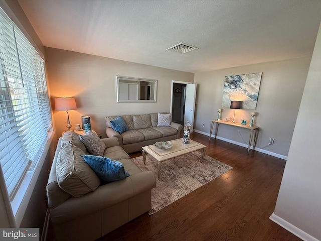 living area with baseboards, visible vents, and wood finished floors