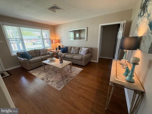 living area featuring baseboards, visible vents, and wood finished floors