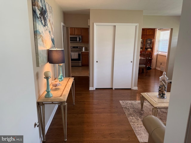 hallway featuring dark wood-type flooring and baseboards